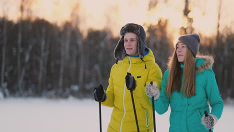 In-the-winter-forest-at-sunset-a-man-and-a-woman-ski-and-look-around-at-the-beauty-of-nature-and-attractions-in-slow-motion.